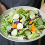 Freshly prepared salad with cucumber, lettuce, carrots, and egg slices presented on a plate.